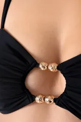 Top de bikini bandeau negro con corte circular y aberturas con cuentas doradas al centro. Breteles semi-amplios y ajustables en la espalda, con recogidos laterales.