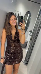 Vestido corto de fiesta confeccionado en tela con lentejuelas color marrón chocolate. Presenta un escote profundo tipo halter y un diseño ajustado al cuerpo.