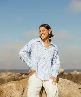 Camisa de manga larga con diseño de rayas verticales finas en color azul y blanco. Presenta cuello clásico, cierre frontal con botones y puños abotonados.