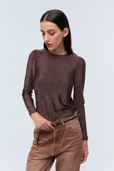 Remera color marrón con lurex, escote redondo, mangas largas con leve frunce en los hombros y corte ajustado.