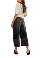 Pantalón de jean negro con lavado gastado, corte ancho, tiro alto, bolsillos delanteros y traseros, y terminación con dobladillo ancho.