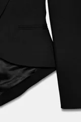 Blazer asimétrica de Zara Woman Collection, confeccionada con mezcla de lana. Presenta cuello solapa, manga larga con botones, cierre frontal con un botón y bajo asimétrico con abertura. Incluye forro interior a tono.