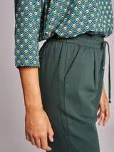 Pantalón de vestir verde oscuro, de corte recto, con cintura elástica ajustable con cordones, bolsillos laterales y ruedo con dobladillo.