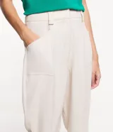 Pantalón de vestir de tiro alto, color beige claro, de corte recto y largo al tobillo. Presenta pinzas marcadas en el frente y bolsillos tipo parche en la parte superior.