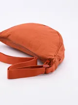Morral tipo bandolera de diseño semicircular, confeccionado en tela técnica color rojo. Cuenta con cierre superior y correa ajustable al tono.