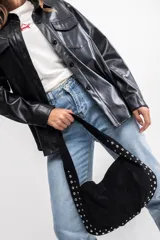 Cartera negra de poliéster con diseño de tachas metálicas plateadas en los bordes y en la correa. Tiene cierre superior y un compartimento principal.