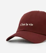 Gorra de sarga color bordó con ala curva y la frase "C'est la vie" bordada en blanco en el frente.