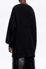 Jersey largo de punto negro con escote en V profundo adornado con detalles de encaje. Presenta mangas largas con puños ajustados y un diseño de tejido acanalado.