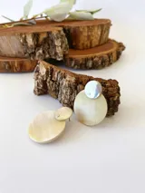 Aros colgantes con base plateada y dije circular de guampa color crema.