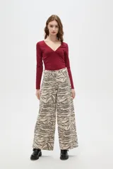 Pantalon de jean de corte ancho y tiro alto, con estampado animal print tipo cebra en tonos beige y gris.
