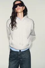 Sudadera de corte holgado con capucha ajustable mediante cordones con detalle de perlas en los extremos. Presenta mangas largas con puños elásticos y bajo con acabado tipo globo.