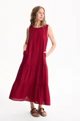 Vestido largo negro de lino, sin mangas, con escote redondo y diseño fluido con volados escalonados en la falda.