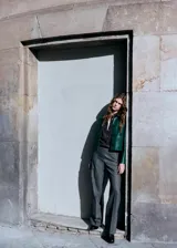 Chaqueta de efecto piel en color verde oscuro, con diseño corto y recto, cuello camisero, manga larga, bolsillos delanteros de parche con solapa y cierre frontal de botones ocultos.