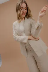 Blazer de lino color beige, de corte estructurado con solapas clásicas, cierre frontal y bolsillos laterales con solapa.