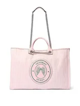 Bolso tipo shopper de Victoria's Secret, confeccionado en lona con diseño a rayas rosadas y blancas. Cuenta con asas de mano y correas de hombro con cadena metálica. Incluye un parche circular con el logo de la marca y alas bordadas en el centro.