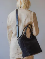 Bolso tipo shopper de gamuza color negro, forrado en su interior. Cuenta con asas de mano y una correa larga desmontable para llevar al hombro o cruzado.