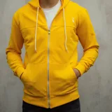 Campera con capucha amarilla con cierre frontal, bolsillos laterales y cordones blancos. Tiene un pequeño logo bordado en el pecho.