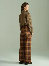 Pantalón ancho a cuadros escoceses en tonos azul, verde y rojo. Tiro alto, con cierre y botones invisibles en el interior y pasacinto de la misma estampa.