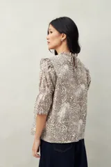 Blusa color beige con estampado abstracto en blanco, corte relajado, mangas 3/4 fruncidas y cuello con volados.