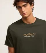 Remera negra de corte comfort, con cuello redondo, manga corta y estampa lettering en el pecho con diseño de montañas y el texto "WILD AND FREE".