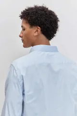 Camisa de corte regular, color celeste con rayas verticales blancas muy finas, cuello clásico y mangas largas con puños abotonados.