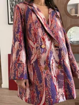 Blazer vestido de corte oversize y manga larga, con cuello de solapa y doble botonadura dorada. Confeccionado en tela jacquard texturada con estampado multicolor.