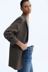 Blazer largo de botonadura sencilla con solapas de muesca, hombreras, pinzas en la cintura y bolsillos delanteros ribeteados. Presenta mangas tres cuartos con diseño remangado y forro interior.