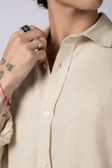 Camisa de manga larga confeccionada en lino, color verde oliva, con cuello clásico y cierre frontal de botones.