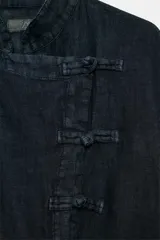 Blusa de lino color azul marino, de manga larga y cuello subido, con cierre frontal cruzado mediante nudos de tela y tiras para lazar en la cintura.