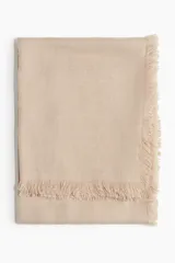 Bufanda grande color beige, de tejido suave y cálido con acabado desflecado.