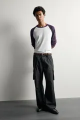 Pantalón cargo de corte relaxed fit, color negro con efecto lavado y estampado de salpicaduras blancas. Cuenta con bolsillos laterales con solapa en las perneras, pinzas en las rodillas y cierre frontal con botón y cremallera.