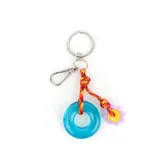 Llavero con argolla metálica y mosquetón, compuesto por un cordón trenzado multicolor que sostiene un dije circular de acrílico traslúcido color celeste y un dije pequeño en forma de flor lila con centro amarillo y la inscripción XL.