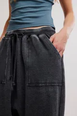 Pantalón harem amplio color gris oscuro con efecto lavado, tiro caído, cintura elástica con cordón de ajuste y grandes bolsillos parche en la parte delantera.