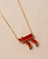 Collar de acero con baño de oro y dije en forma del símbolo Jai esmaltado en rojo, con cadena fina de eslabones.