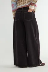 Jean de corte wide leg con diseño de costuras verticales decorativas en el frente, tiro medio y cierre frontal con botón y cremallera.