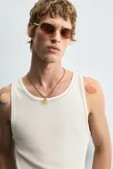 Camiseta tipo tank top de corte slim fit, color blanco hueso, con cuello redondo amplio y sisas terminadas con pespunte contrastante en color oscuro.