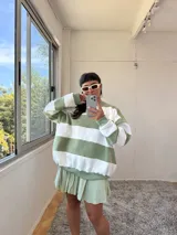 Buzo de corte oversize con diseño de rayas horizontales anchas en color verde y crudo. Presenta cuello redondo, mangas largas y puños elásticos, confeccionado en tela con interior de felpa.