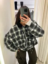 Chaqueta de denim en color gris oscuro, con corte oversize, mangas amplias, cuello camisero y bolsillos frontales con solapa.