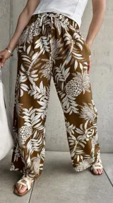 Pantalón marrón con estampado de hojas y flores blancas, de corte holgado y cintura elástica con lazo.