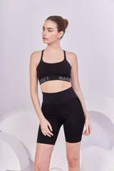 Top deportivo negro con breteles finos y elástico inferior con la marca Bassi estampada en gris. Diseño de espalda cruzada que brinda soporte y sujeción.