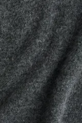 Chaleco de punto gris oscuro, sin mangas, con cuello camisero y tapeta de botones. Presenta un acabado de punto acanalado en las sisas y el bajo.