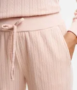 Conjunto de pijama largo color rosa claro texturizado, compuesto por un buzo de cuello redondo y un pantalón con cintura con lazo.