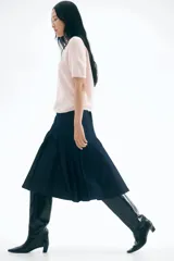 Buzo de punto fino color rosa pálido, con cuello redondo y mangas cortas. Presenta remates acanalados en el cuello, puños y bajo.