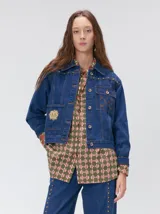 Campera denim crop de mezclilla oscura, con apliques metálicos en el pecho, bolsillos delanteros cruzados con detalles bordados y de parches.
