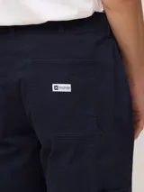 Pantalón de corte recto color azul marino, con bolsillos diagonales en el delantero, bolsillos traseros y detalles de bolsillos estilo carpintero en las piernas.