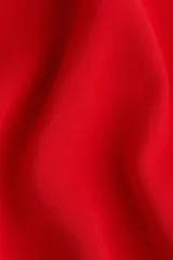 Vestido midi rojo de manga larga, con escote redondo y corte evasé con nesgas laterales para dar volumen.