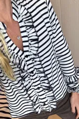 Blusa de manga larga a rayas verticales blancas y negras con volados en el frente y en el escote.