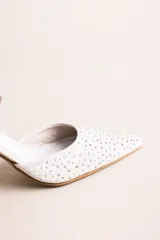 Zapato de tacón alto estilo slingback con tira al tobillo ajustable, color blanco con pedrería de strass aplicada en la puntera afilada y tacón escultórico de diseño acampanado.
