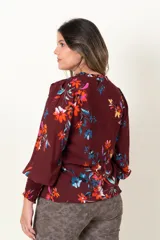 Blusa color borgoña con estampado de flores multicolores, escote en V con botones forrados, mangas largas con frunces en los puños y hombros.