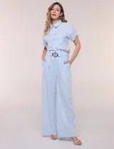 Conjunto de dos piezas confeccionado en lino, de estilo casual safari. Incluye camisa de manga corta con cuello camisero con bordado festoneado, abotonadura frontal y bolsillos en el pecho; y pantalón palazzo de tiro alto con bolsillos y cinturón con hebilla metálica dorada.